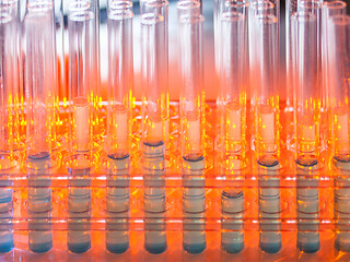 Image showing Glass test tubes containing blue liquid on warm orange background.