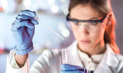 Image showing Young scientist pipetting in life science laboratory.