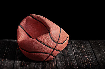 Image showing Deflated and rumpled old ball on a wooden floor