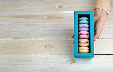 Image showing Female hand holds gift box with macaroons