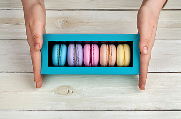 Image showing Female hands holding box with macaroons