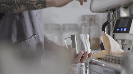 Image showing The hands of a young barista guy make steam for whipping milk in a mug. Full HD video, 240fps, 1080p.