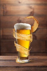 Image showing Glass of light fresh beer with flying spiral splash around mug.