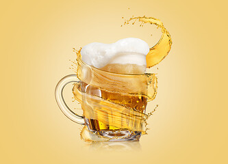 Image showing Flying spiral splash around mug of light fresh beer with thick foam.