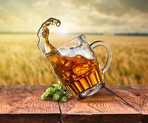 Image showing Glass of beer on wooden table with sea on background