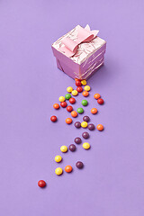 Image showing A ripped gift box with colorful candy on a purple background.