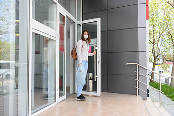 Image showing Girl walks out of the store wearing a medical mask with shopping