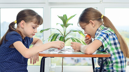 Image showing Children at home at the table collect puzzle puzzles