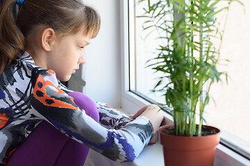 Image showing Upset girl sitting by the window and looking very sad out the window