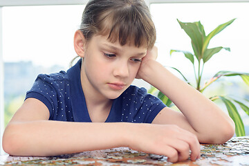 Image showing Tired girl collects puzzle for a long time