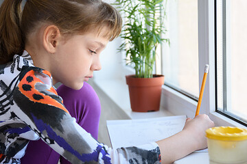 Image showing Upset girl sitting by the window and looking very sad out the window