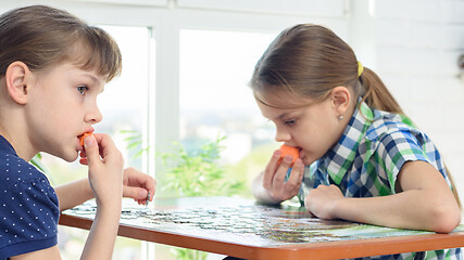 Image showing Children collect puzzles and snack on carrots