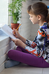 Image showing Passionate girl at home paints a landscape sitting on the floor by the window