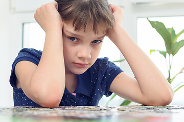 Image showing The sad girl cannot assemble a puzzle