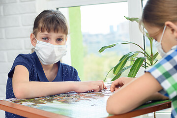 Image showing A girl in a medical mask plays board games and looked into the frame.