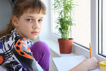 Image showing Girl spending time at home in quarantine, girl draws while sitting by the window