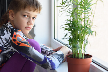 Image showing Sad girl at home alone, draws with pencils on the windowsill