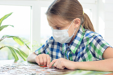 Image showing Teen girl in a medical mask collects a puzzle in a detention center