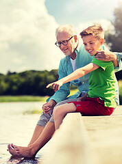 Image showing grandfather and grandson sitting on river berth