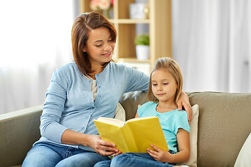 Image showing happy girl with mother reading book at home