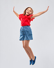 Image showing happy smiling girl in red shirt and skirt jumping