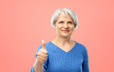 Image showing smiling senior woman r showing thumbs up over pink