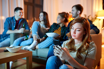 Image showing sad young woman with smartphone at home party