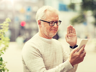 Image showing senior man having video call on smartphone in city