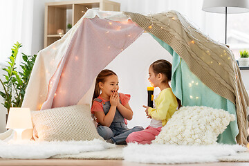 Image showing girls playing with torch in kids tent at home