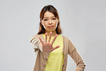 Image showing young asian woman showing stop gesture