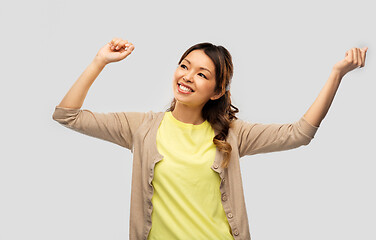 Image showing happy asian woman dancing over grey background