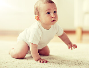 Image showing little baby in diaper crawling on floor at home