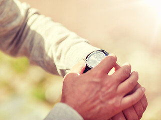 Image showing senior man checking time on wristwatch outdoors