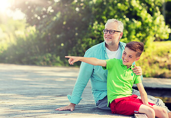 Image showing grandfather and grandson sitting on river berth