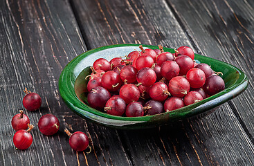 Image showing Red gooseberries on a dark table