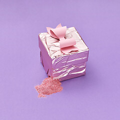 Image showing A ripped gift box with colorful candy on a purple background.