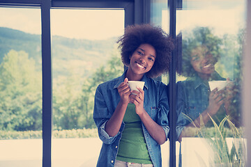 Image showing African American woman drinking coffee looking out the window