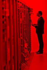 Image showing businessman with laptop in network server room