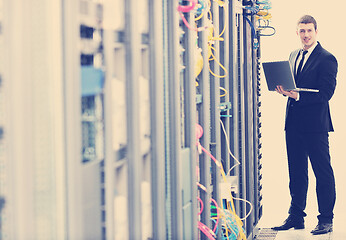 Image showing businessman with laptop in network server room