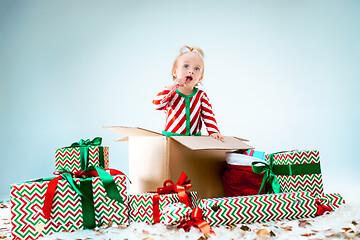 Image showing Cute baby girl 1 year old sitting at box over Christmas background. Holiday season.