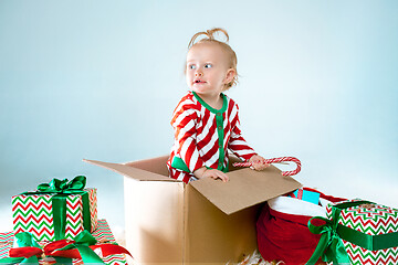 Image showing Cute baby girl 1 year old sitting at box over Christmas background. Holiday season.