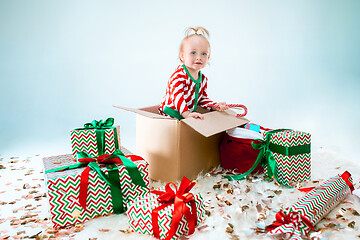 Image showing Cute baby girl 1 year old sitting at box over Christmas background. Holiday season.