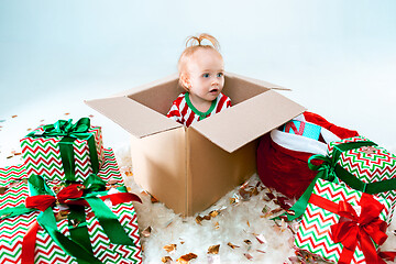 Image showing Cute baby girl 1 year old sitting at box over Christmas background. Holiday season.