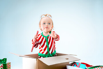 Image showing Cute baby girl 1 year old sitting at box over Christmas background. Holiday season.