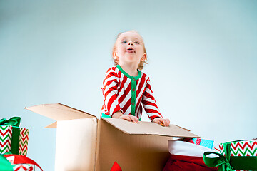 Image showing Cute baby girl 1 year old sitting at box over Christmas background. Holiday season.