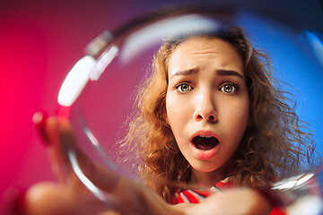 Image showing The surprised young woman in party clothes posing with glass of wine.