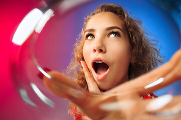 Image showing The surprised young woman in party clothes posing with glass of wine.