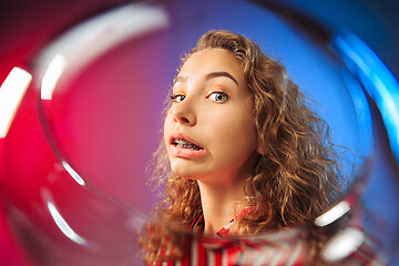 Image showing The surprised young woman in party clothes posing with glass of wine.