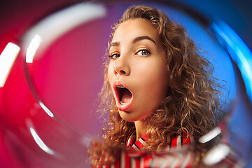 Image showing The surprised young woman in party clothes posing with glass of wine.