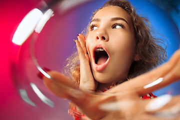 Image showing The surprised young woman in party clothes posing with glass of wine.